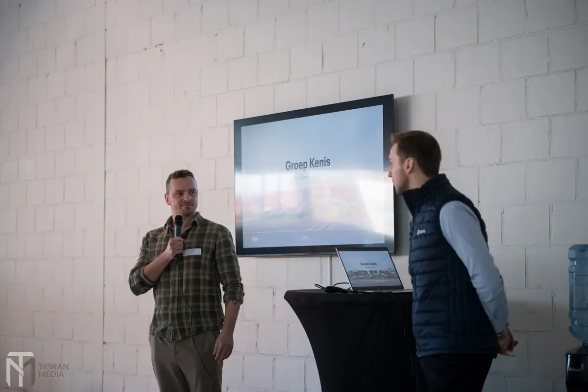 Spreker presenteert Groep Kenis op groot scherm tijdens Open Coffee event